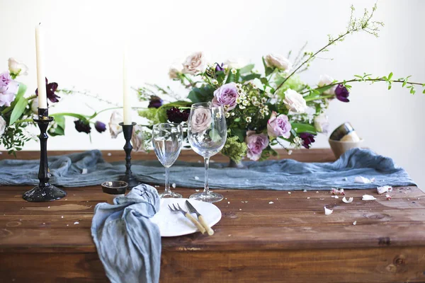 Bouquets of pink flowers on a table set for dinner with candles — Stock Photo, Image