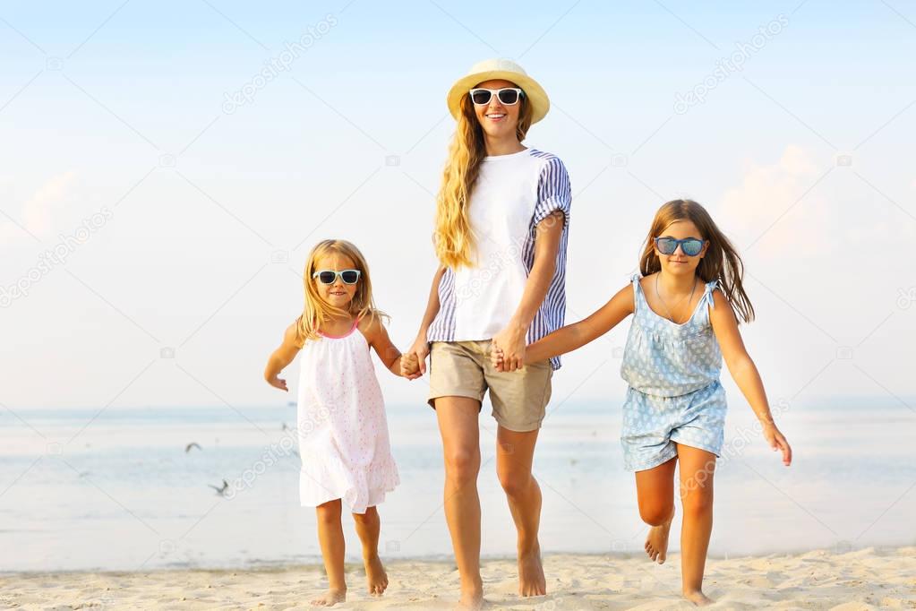 Happy young family having fun running on beach at sunset. Family