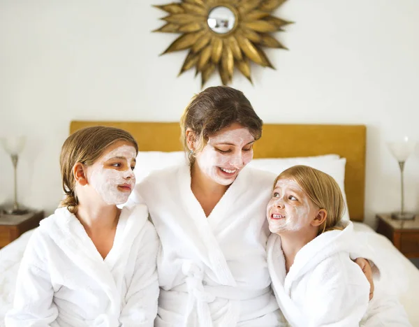 Mãe feliz e meninas em roupões de banho com máscara creme — Fotografia de Stock