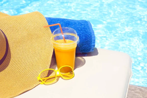 Swimming pool, orange juice, beach towel, sunglasses — Stock Photo, Image