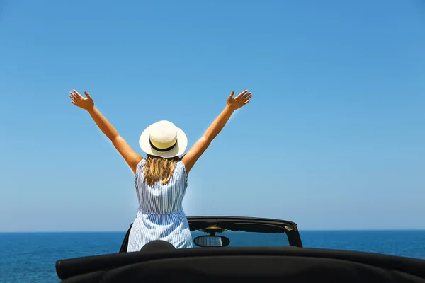 Glückliche junge Frau im Auto am Strand — Stockfoto