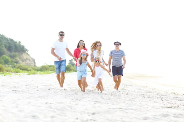 Grupo de amigos com crianças correndo na praia — Fotografia de Stock