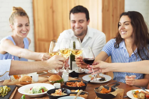 Handen met witte wijn roosteren boven geserveerd tafel met voedsel — Stockfoto