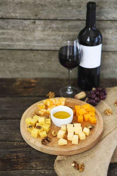 Trauben, verschiedene Käsesorten mit einem Glas Rotwein — Stockfoto