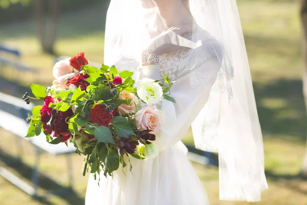 Молодая невеста в белом свадебном платье держит красивый букет — стоковое фото