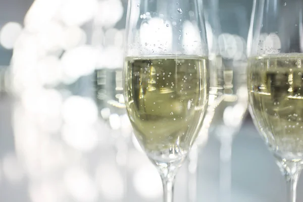 Шампанські окуляри на білому тлі в яскравих вогнях — стокове фото