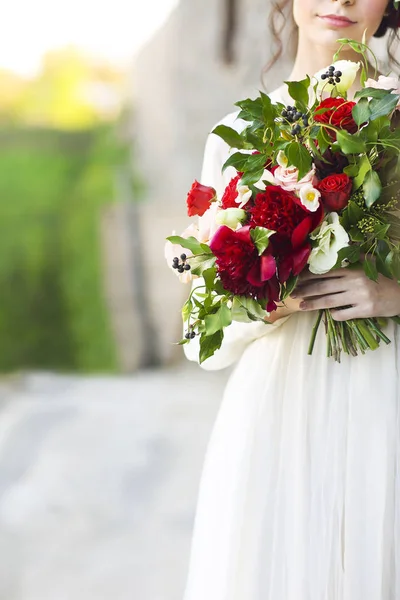 Novia en vestido de novia blanco celebración de ramo hermoso sobre desenfoque —  Fotos de Stock