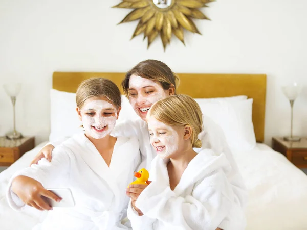 Mãe feliz e meninas em roupões de banho na cama — Fotografia de Stock