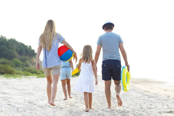 Ung familj ha kul körs på stranden vid solnedgången. — Stockfoto