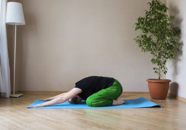 Orta yaşlı kadın evde yoga yapıyor.