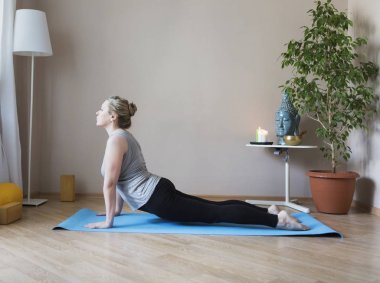 Orta yaşlı kadın evde yoga yapıyor.