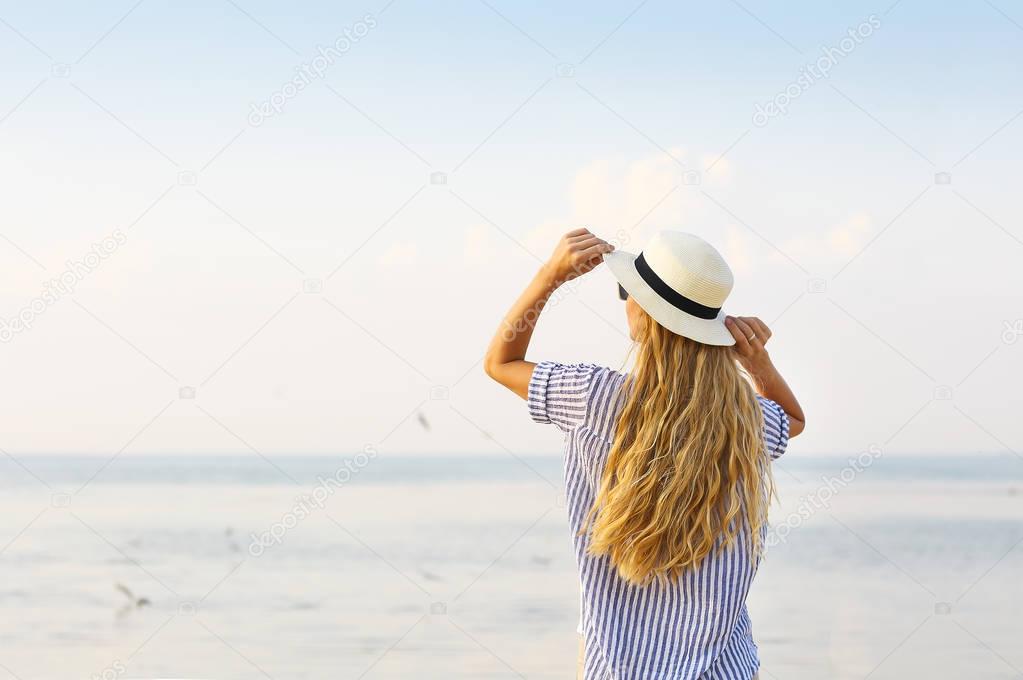 Woman on beach wearing white hat 