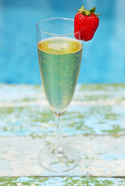 Copo de champanhe com morango no fundo turquiose — Fotografia de Stock