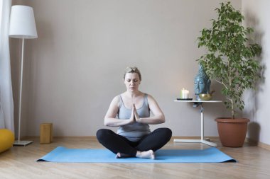 Orta yaşlı kadın evde yoga yapıyor.