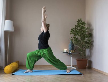 Orta yaşlı kadın evde yoga yapıyor.