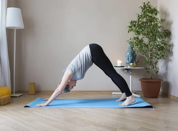 Orta yaşlı kadın evde yoga yapıyor.