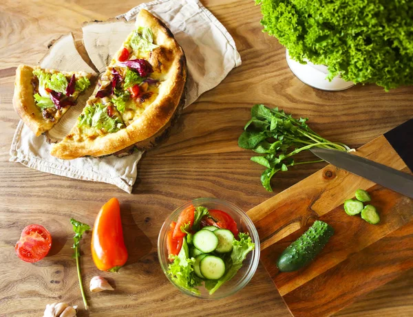 Pizzę domowej roboty i warzywa na drewnianym stole — Zdjęcie stockowe