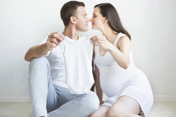 Young man and pretty pregnant woman with baby wear — Stock Photo, Image