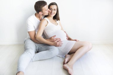 Genç adam ve çok hamile kadın birlikte sarılma