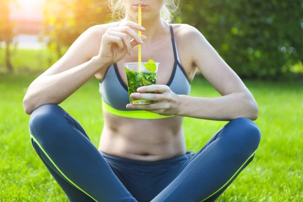 Donna che beve dopo l'allenamento di fitness durante la giornata estiva . — Foto Stock