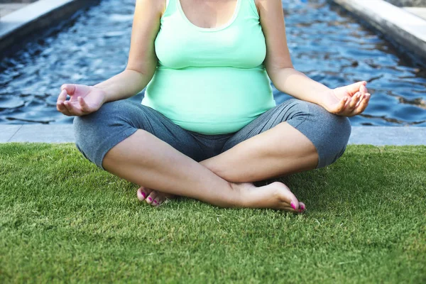 Yaz Park'ta güzel bir hamile kadın meditaiting — Stok fotoğraf