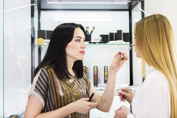 Joven mujer bonita y consultora de belleza en la tienda —  Fotos de Stock