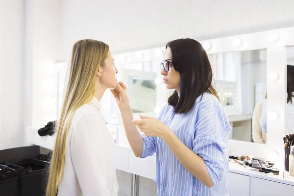 Joven artista de maquillaje haciendo cambio de imagen a modelo bonito —  Fotos de Stock