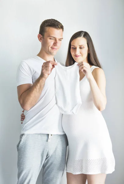Hombre joven y bonita mujer embarazada con ropa de bebé —  Fotos de Stock