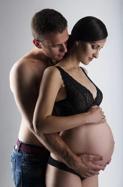 Ung man och ganska gravid kvinna omfamnar — Stockfoto