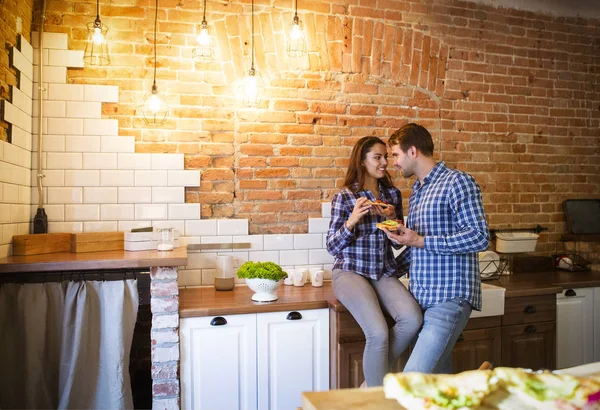 Junger Mann und Frau kochen und essen gemeinsam in der Küche — Stockfoto