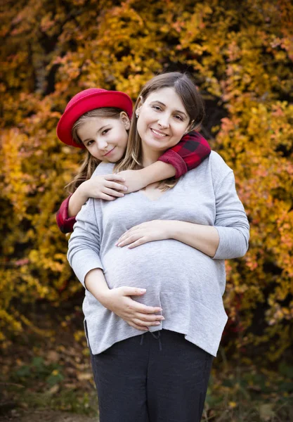 Jovem mãe grávida feliz com filha no parque de outono — Fotografia de Stock