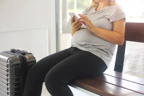 Zwangere jongedame met koffer op luchthaven — Stockfoto