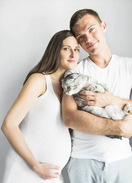 Young man with pregnant woman and cat indoors — Stock Photo, Image