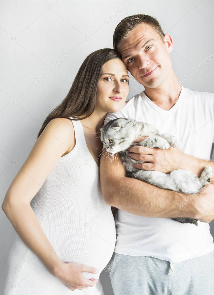 Young man with pregnant woman and cat indoors