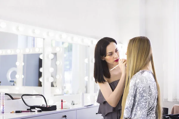 Joven artista de maquillaje haciendo cambio de imagen a modelo bonito —  Fotos de Stock