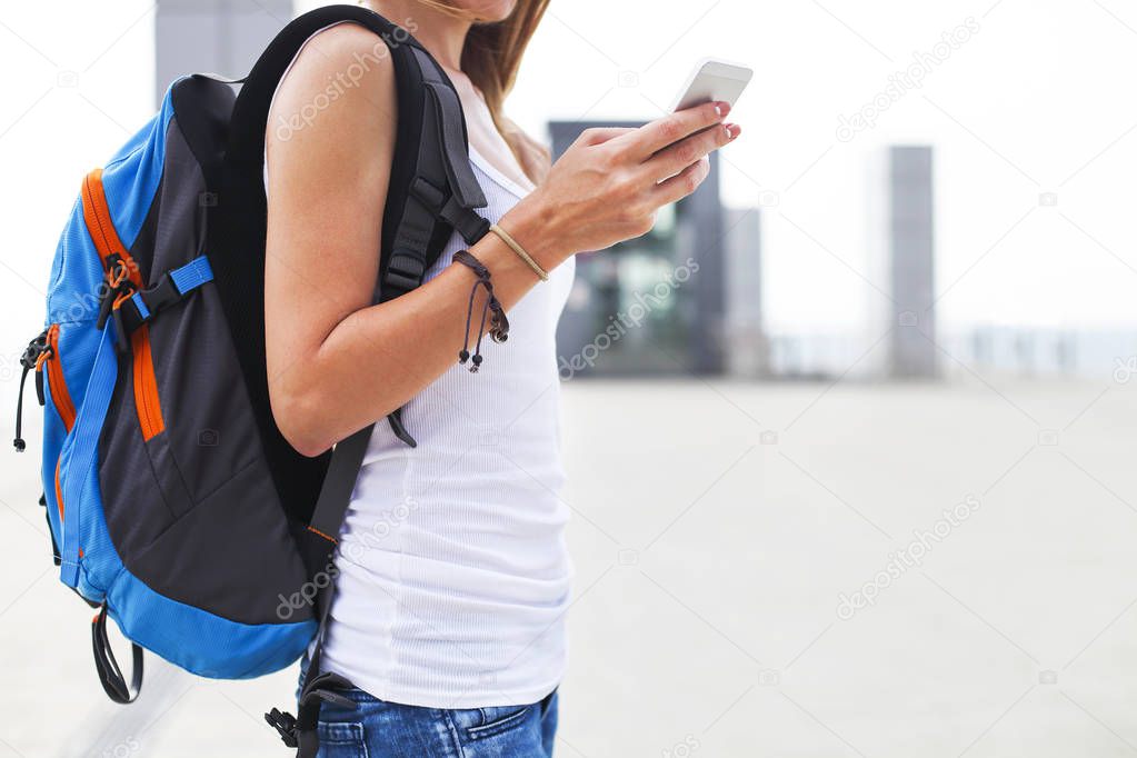 Young pretty girl with backpack using phone