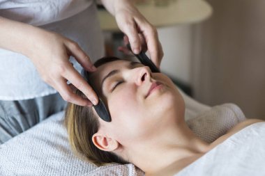 Genç kadın güzellik kliniğinde yüz bakımı görüyor.