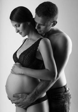 Genç adam ve çok hamile kadın kucaklama
