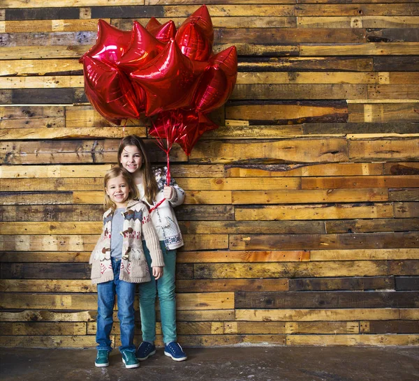 Дети с воздушными шарами у деревянной стены — стоковое фото