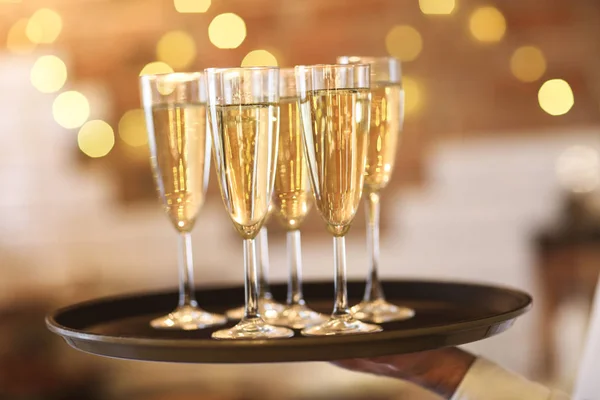 Champagne glasses on tray in bright lights — Stock Photo, Image