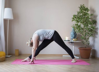 Orta yaşlı kadın evde yoga yapıyor.