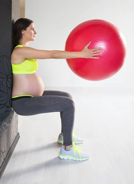 Een jonge zwangere vrouw doen fitness oefeningen — Stockfoto