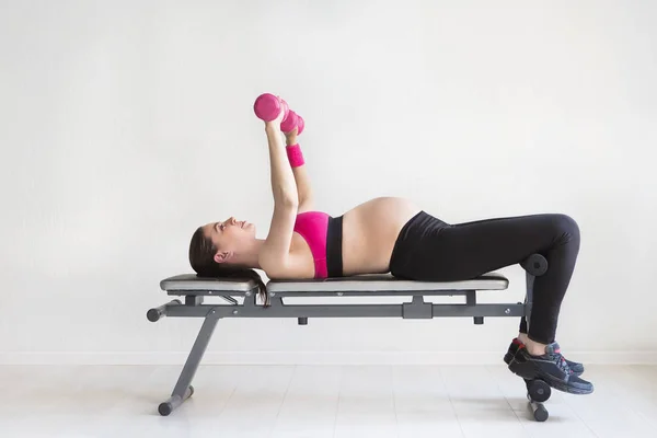 Eine junge schwangere Frau macht Fitnessübungen — Stockfoto