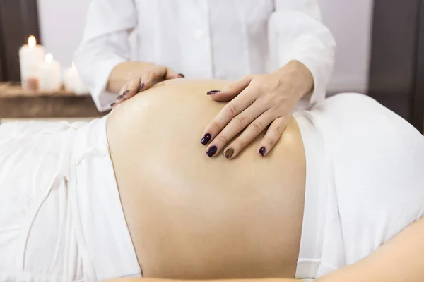 Молодая беременная женщина получает массаж в спа — стоковое фото
