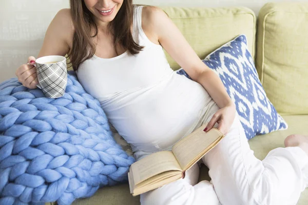 Joven bonita mujer embarazada sentada en el sofá —  Fotos de Stock