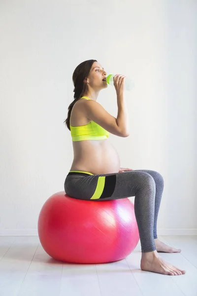 Young pretty pregnant woman sitting on fitness ball — Stock Photo, Image