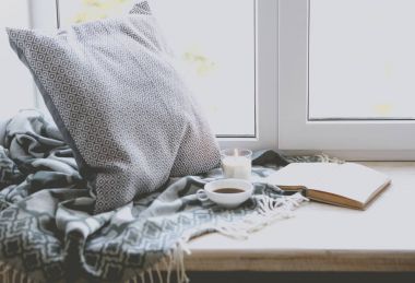 Fincan kahve, mum ve kitap pencere yakınındaki