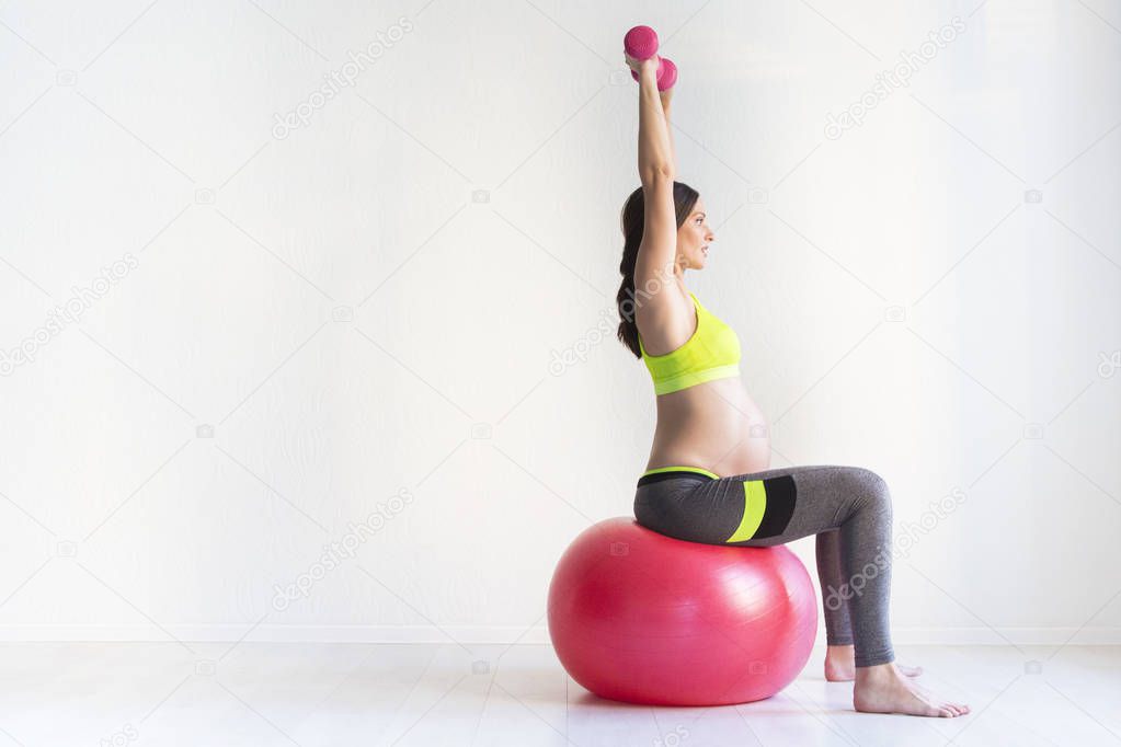 One young pregnant women doing fitness exercises