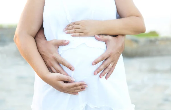 Uomo e giovane donna incinta che si abbracciano all'aperto — Foto Stock