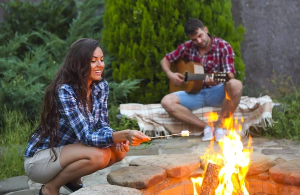 Mladý pár s kytarou u ohně venku — Stock fotografie